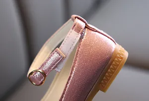 Macro view of girl's glitter Mary Jane shoe showing velcro strap and gold buckle