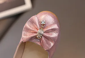 Dettaglio di scarpe da principessa rosa glitterate con fiocco e ciondolo di strass