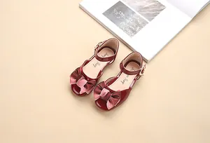 Dettaglio di scarpe Mary Jane rosse in vernice per bambina con doppio fiocco di raso