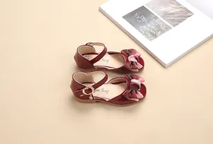 Dettaglio scarpe da principessa in vernice rosso scuro con fiocco di velluto e fibbia d'oro