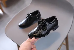 Details von schwarzen Jungen-Halbschuhen mit glänzender Schlangenstruktur und Schnürung