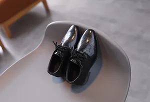 Detail von Jungen-Lacklederschuhen in Schwarz mit eleganter Schuppenstruktur und Schnürung
