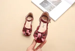 Dettaglio di scarpe Mary Jane in vernice bordeaux con grande fiocco in velluto rosa per bimba