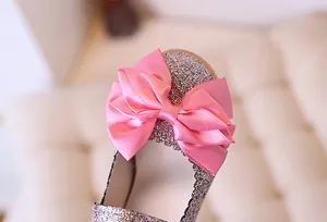 Macro detail of sparkly silver glitter kids shoes with a large pink satin bow decoration