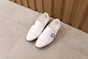 Macro detail of white monk strap boy shoes with woven texture and silver buckle