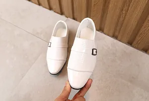 Detail of white boy's monk strap dress shoes with glossy finish and metal buckle