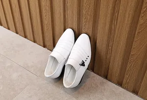 Dettaglio scarpe eleganti da bambino in pelle bianca con fibbia e borchie in metallo