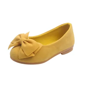 Dettaglio di scarpe gialle per bambine in finta pelle scamosciata con un grande fiocco