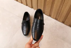 Dettaglio scarpe eleganti nere da bambino con rivetti argento e pelle opaca
