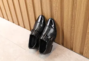 Detail of boys' black monk strap leather shoes with glossy toe and woven texture finish
