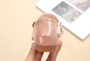 Dettaglio di scarpe Mary Jane in vernice rosa con ciondolo metallico e cinturino velcro