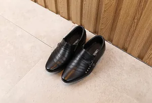 Dettaglio di scarpe stringate nere da ragazzo con cuciture e rivetti in metallo