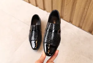Detail of boys' black formal loafers with patent leather texture and metal buckle strap