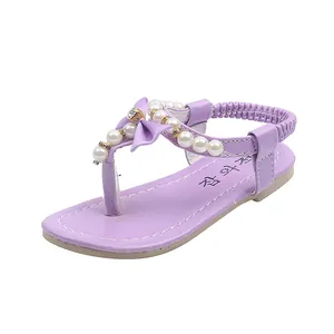 Detalle de sandalias moradas para niñas con perlas blancas y lazo decorativo elegante