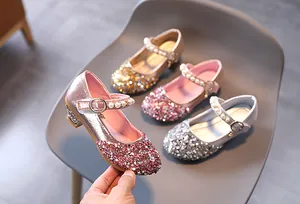 Dettaglio di scarpe Mary Jane glitterate da bambina con fibbia di perle in vari colori