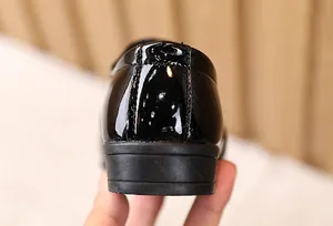 Macro detail of glossy black patent leather child dress shoes with neat stitching