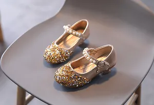 Dettaglio scarpe da festa dorate per bambina con paillettes e cinturino di perle