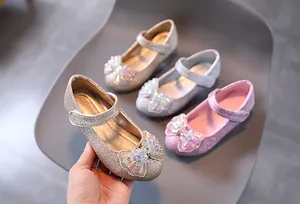 Dettaglio di scarpe Mary Jane glitterate da bambina con fiocchi di cristallo e velcro