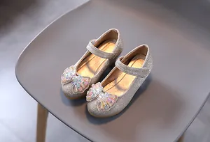 Dettaglio di scarpe Mary Jane dorate con paillettes, fiocco di perline e glitter