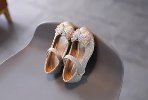 Dettaglio di scarpe Mary Jane dorate con paillettes per bambina con fiocco di strass e perle