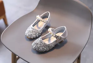 Dettaglio delle scarpe argentate con paillettes da bambina con cinturino di perle e tacco