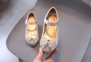 Dettaglio delle scarpe Mary Jane dorate da bambina con fiocco di perline e glitter