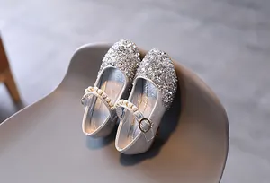 Dettaglio macro di ballerine argentate con paillettes da bambina e cinturino di perle