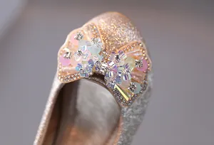 Dettaglio ravvicinato delle scarpe glitterate da bambina con fiocco floreale perlato