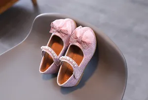 Détail de ballerines roses scintillantes avec nœud en tulle et bride perlée pour fille