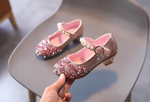 Dettaglio di scarpe rosa da principessa con paillettes, perle bianche e ciondolo di cristallo