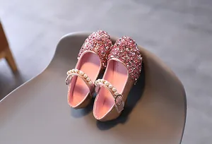 Dettaglio delle scarpe Mary Jane con paillettes rosa e cinturino con perle per bambine
