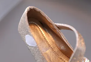 Dettaglio macro dei glitter champagne dorati e delle cuciture sulle scarpe eleganti bimba