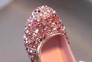 Dettaglio di strass rosa e perle bianche su scarpe da principessa oro rosa