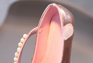 Dettaglio macro di scarpa da bambina rosa metallizzato con cinturino di perle e velcro