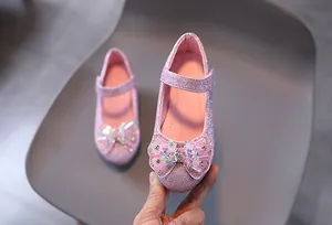 Dettaglio di scarpe da principessa rosa con paillettes per bambine e fiocco decorato