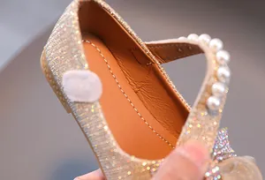 Détail de chaussures Mary Jane dorées pour enfants avec bride en perles et doublure cousue