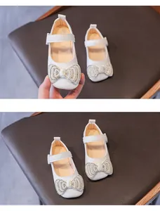 Dettaglio di scarpe Mary Jane bianche da bambina con fiocco di perle e strass