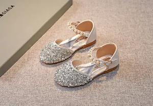 Detail von silbernen Mädchen-Prinzessin-Schuhen mit Perlenriemen und Glitzereffekt