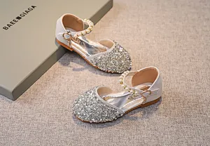 Detail von glitzernden Silberpailletten und Perlenriemen an Prinzessinnenschuhen für Mädchen