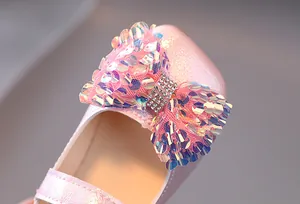 Détail de chaussures roses pour filles avec nœud en paillettes et boucle en strass