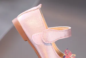 Détail de chaussures roses nacrées pour filles avec fleurs à paillettes et velcro