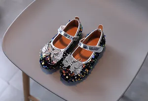 Detailed view of girls' black sequin Mary Jane shoes with rhinestone bow and velcro strap
