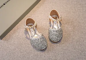 Detail von silbernen Pailletten-Ballerinas für Mädchen mit Perlenriemen und Metallschnalle