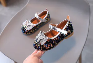 Detail of girls' black sequin Mary Janes with sparkling rhinestone bow and non-slip sole