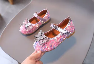 Close-up of pink sequined girls Mary Jane shoes with rhinestone bow and velcro strap