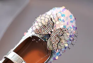 Macro shot of glittering iridescent sequins and rhinestone bow on girls' princess shoes