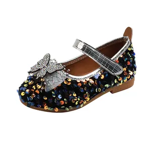 Close-up of glitter sequins and rhinestone bow detail on black Mary Jane shoes