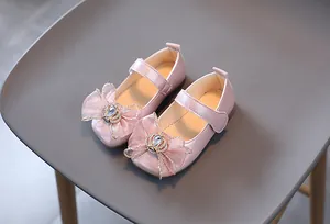 Detail eines rosa metallischen Mary-Jane-Schuhs mit Netzschleife und Kristallkrone