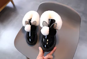 Détail de la botte de neige en cuir verni noir avec col en fourrure et décor oreilles de lapin
