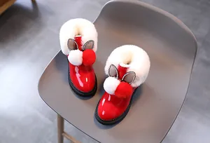 Détail de bottes de neige rouges en cuir verni pour enfants avec fourrure et oreilles de lapin